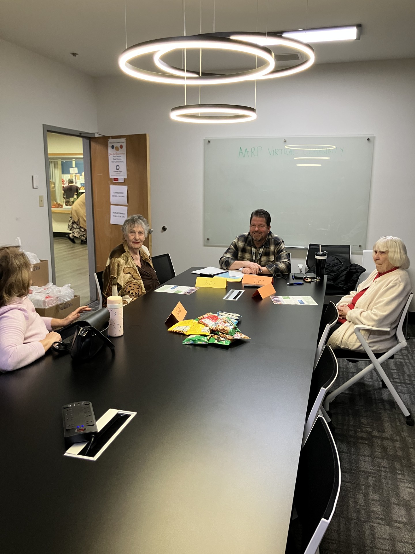 Image of a group of senior citizens sitting at a conference table talking to a worker